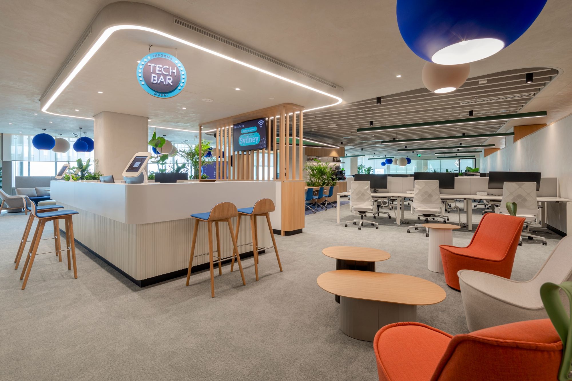 Informa Dubai Tech Bar and open-plan workplace by dwp, combining flexible work settings with timber finishes and contemporary lighting.