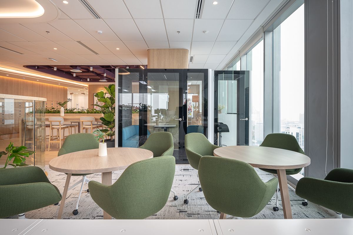 L’Oréal Bangkok office collaboration space with green lounge chairs, meeting pods, natural timber and city view