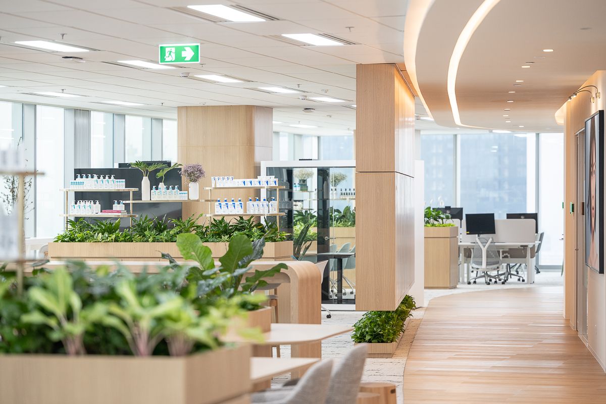 L’Oréal Bangkok workplace interior with integrated product displays, indoor planting, timber finishes and open work areas