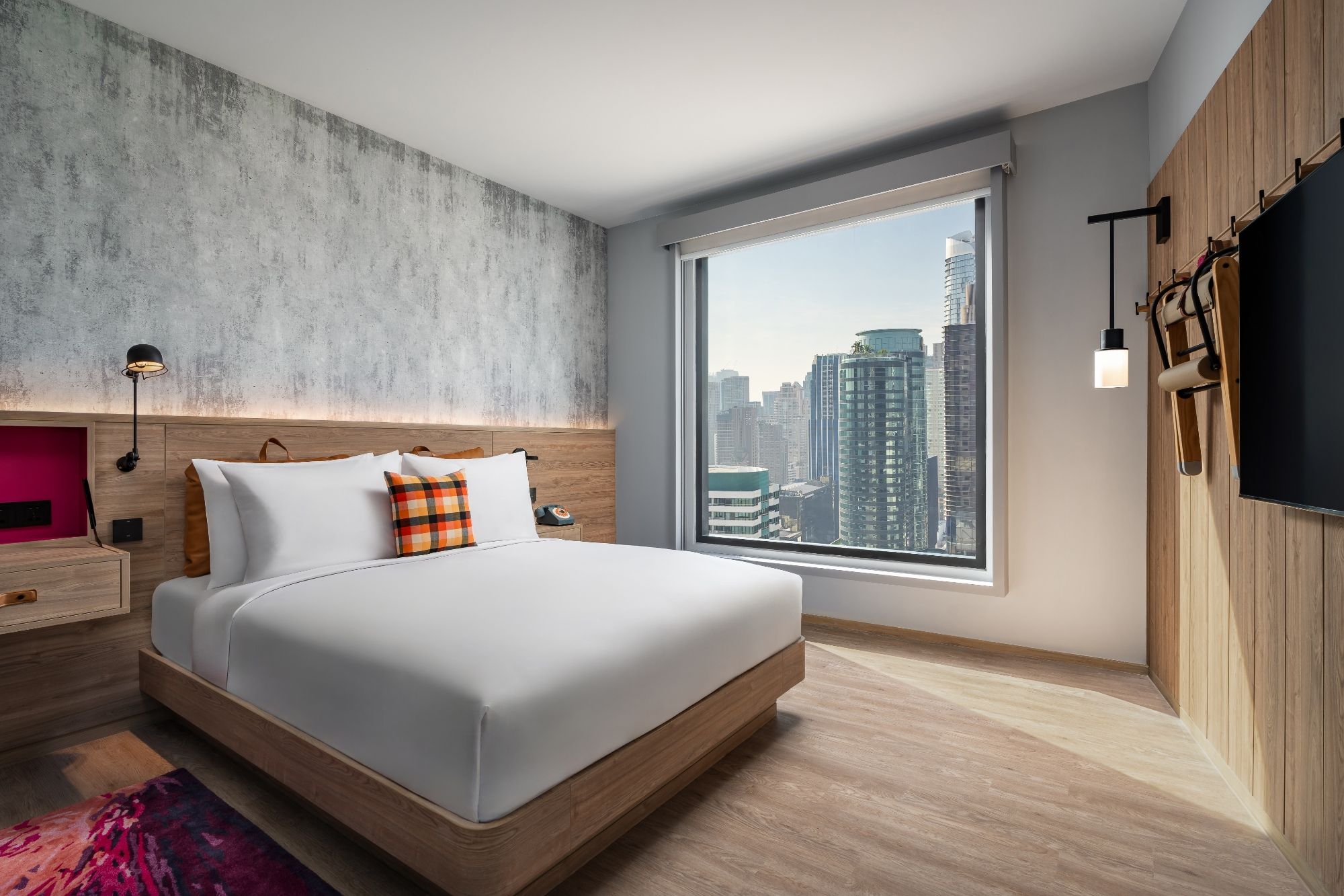 Moxy Bangkok Ratchaprasong guest room with warm timber finishes, contemporary furnishings and Bangkok city views